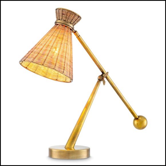 Lampe de Table Kon Ti en rotin naturel, L'abat-jour en rotin repose sur une base à la finition laiton vintage. Lampe de Table Kon Ti en rotin naturel, L'abat-jour en rotin repose sur une base à la finition laiton vintage.